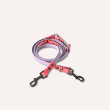 BioThane® original waterproof material, a coiled dog leash with a lavender purple body, bright pink handle and buckle area, and dark metal hardware, shown on a plain light beige background.