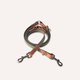 BioThane® original waterproof material, a set of dog leashes with dark gray webbing and warm brown leather accents, featuring antique bronze metal swivel clips, arranged on a light cream background.