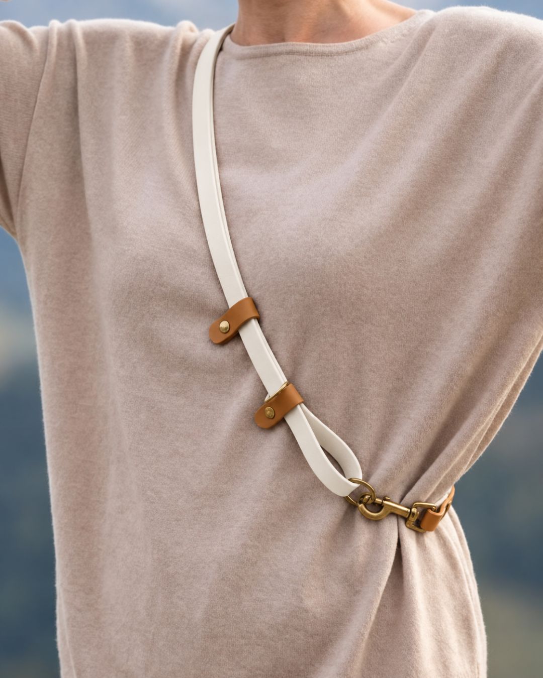FREE worn across the body, showing the BioThane® strap and stoppers with antique brass hardware.