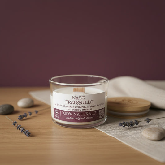 Candle in a glass jar with a label on a wooden surface with lavender and stones.