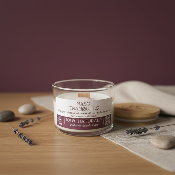 Candle in a glass jar with a label on a wooden surface with lavender and stones.