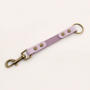 A light purple BioThane® strap keychain with antique bronze hardware, including a swivel clasp and a split ring, shown on a plain off-white background.